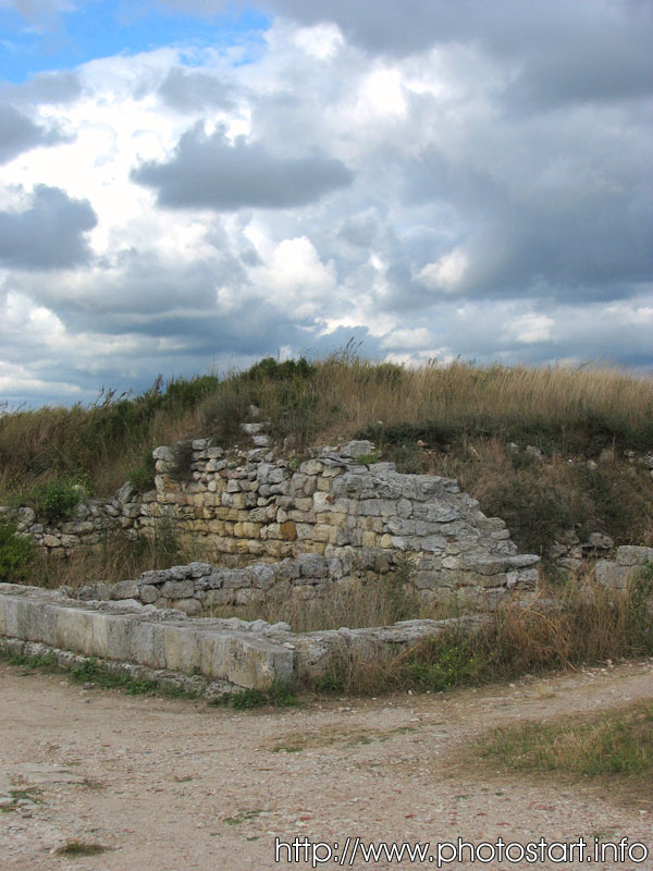 Часть стены и фундамент древнего дома под курганом слева от начала главной улицы